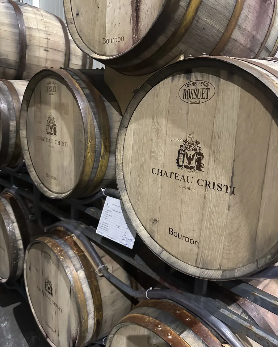 Oak barrels stacked in the Château Cristi cellar, the estate's name branded on each head